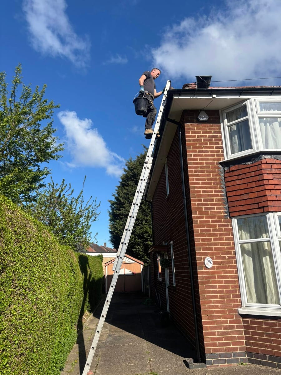 D&G Roofing Derby - roofer on ladder carrying out guttering and fascia work on semi-detached house